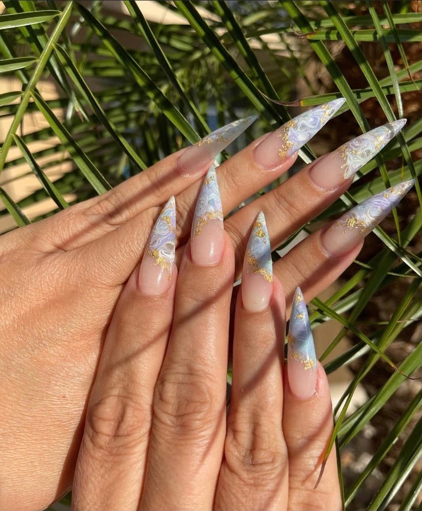 Long stiletto nails with a pearly marble finish and gold flakes, done at Miyu Nails & Spa